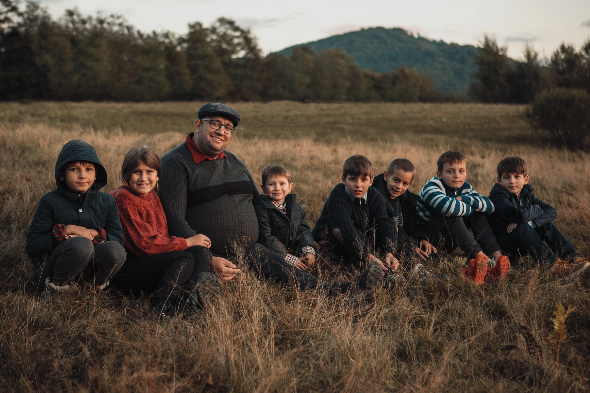 Dragos and group of children sitting in field at sunset